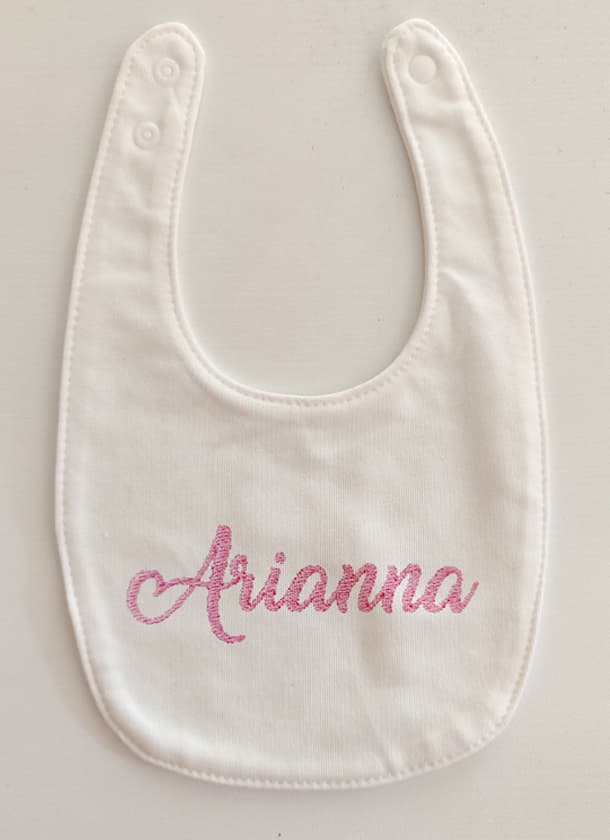 Bavaglino per neonato bianco con ricamato il nome "Arianna" in rosa