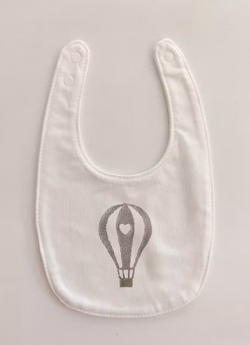 Fotografia di un bavaglino per neonato con una mongolfiera azzurra ricamata sulla parte centrale.