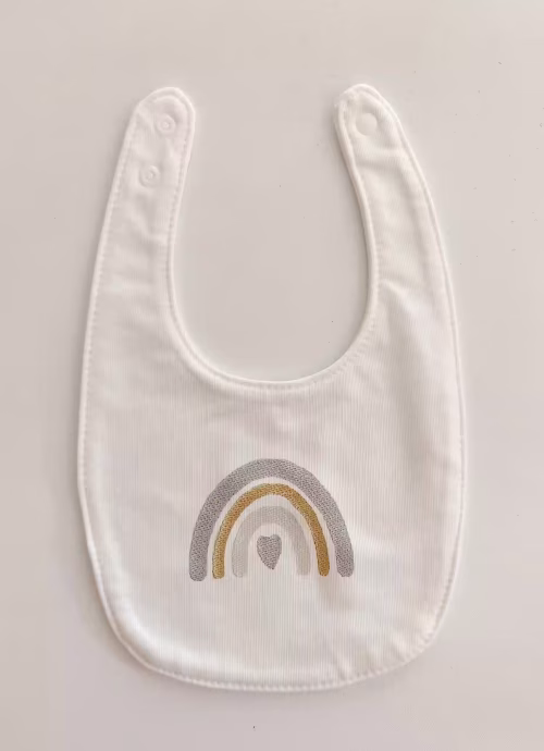 Fotografia di un bavaglino per neonato con un arcobaleno sulle sfumature azzurre ricamato sulla parte centrale.