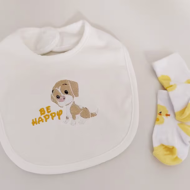 Fotografia di un bavaglino per neonato con il disegno di un cane con scritto accanto "Be Happy"