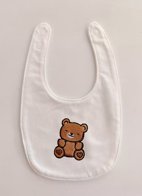 Fotografia di un bavaglino per neonato con un orso marrone ricamato sulla parte centrale.